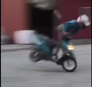 The video begins with a person in a helmet and blue jacket riding a small scooter. They are in an open space featuring a reddish building and several large white bales in the background, all set against an overcast sky.
